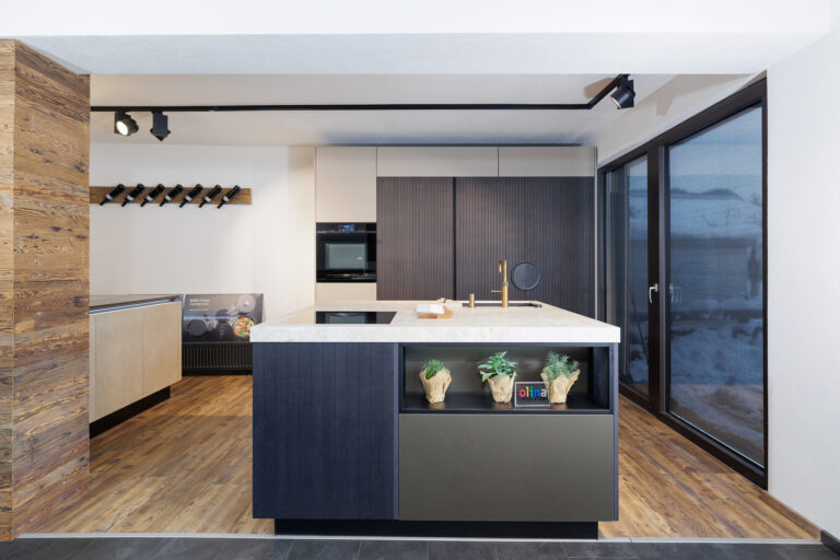 Küche mit beiger Front und Lamellenoptik kombiniert, Kochinsel in quadratischerform und weißer Keramikarbeitsplatte