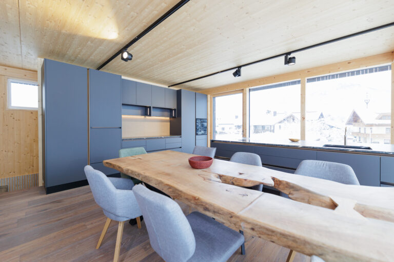 Küche mit matten Fronten in taupe sowie Esstisch mit aus Vollholz mit Naturkante