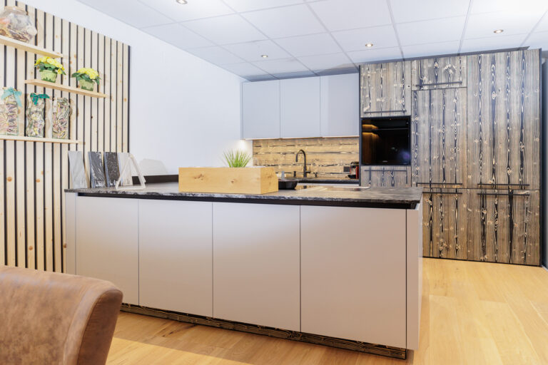 Küchenkombination mit Frontmaerial in weiß und Holzimitat, Insel mit dunkler Natursteinarbeitsplatte