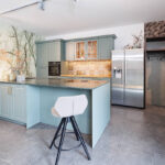 Landhausküche mit mintfarbigen Fronten und heller Natursteinarbeitsplatte