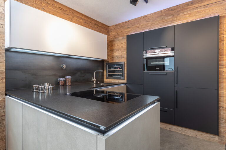 L-Küche in grau, weiß und schwarzer Front kombiniert, schwarze Natursteinarbeitsplatte