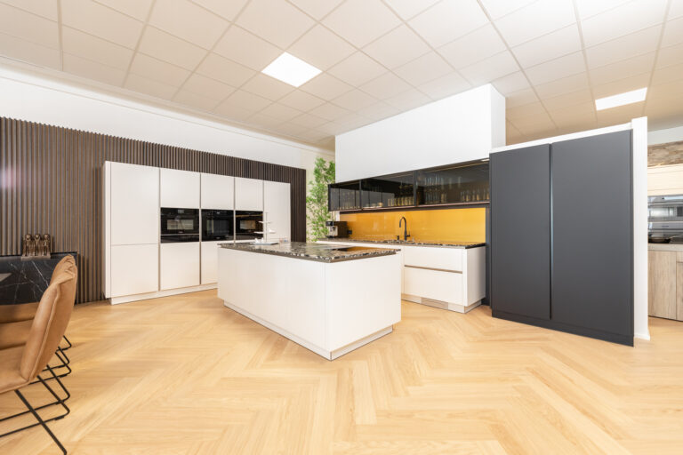 Küche mit weißer Front in matt mit gelber Glasrückwand und Natursteinarbeitsplatte in dunkel