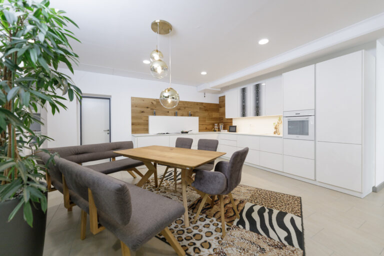 Weiße Küche mit weißer Arbeitsplate und E-Geräten, Esstischgruppe in Eiche hell