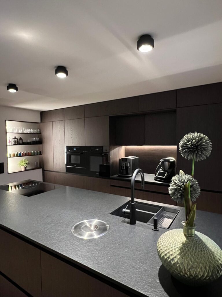 olina Küche mit Naturholzfront dunkel gebeizt, schwarze Granitarbeitsplatte, Bora-Kochfeld