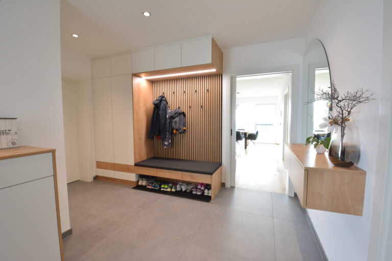 Garderobe in weiß mit Naturholz kobiniert, runder Spiegel mit Sideboard