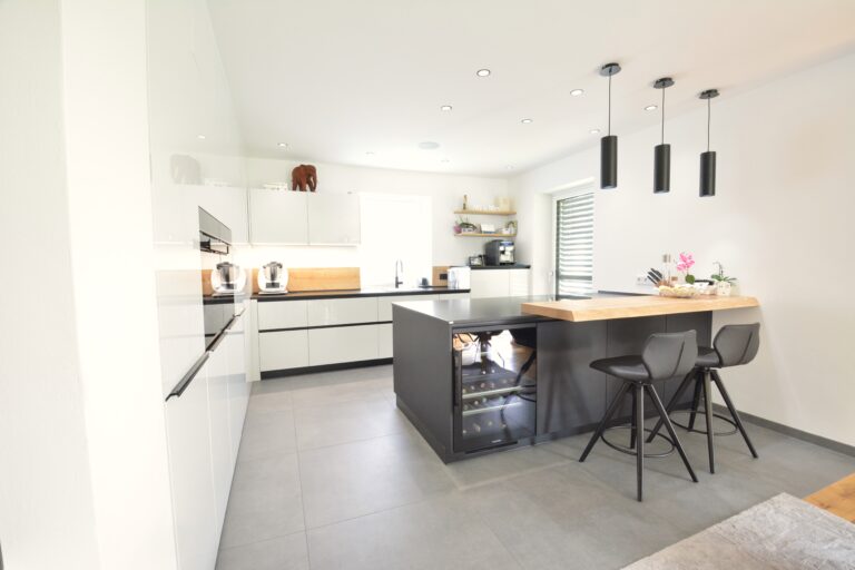 L-Küche mit schwarzer Insel mit verbauten Weinkühlschrank in schwarz, Bartheke mit zwei Stühlen