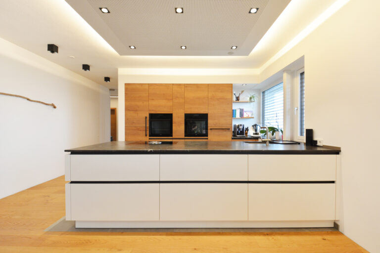 olina L-Küche, Hochschränke funiert mit Wildeiche natur, Küchenarbeitsplatte in schwarzem Naturstein