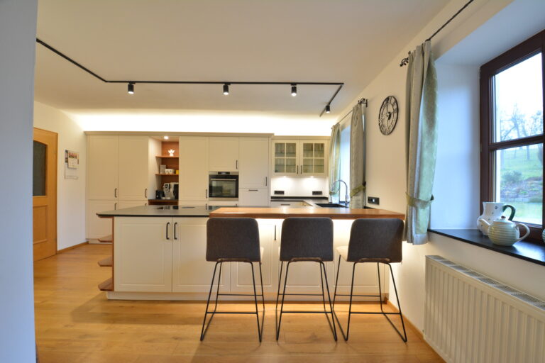 olina Landhausküche weiß mit schwarzen Griffen, Insel mit Thekenlösung und schwarzem Naturstein