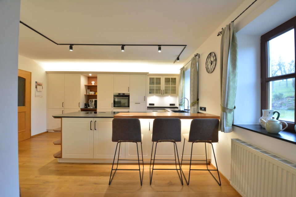 olina Landhausküche weiß mit schwarzen Griffen, Insel mit Thekenlösung und schwarzem Naturstein