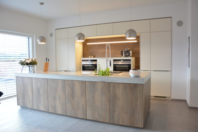 Küche mit weißer Front und Insellösung in dunkler Eichen-Front, kombiniert mit einer aufgedoppelten Arbeitsplatte in Betonoptik