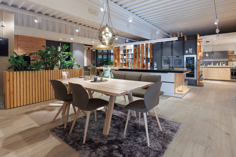 Küche-Esskombination mit Massivholztisch und Stühle sowie eine Küche in schwarz matt und Kochinsel in weiß mit Naturstein