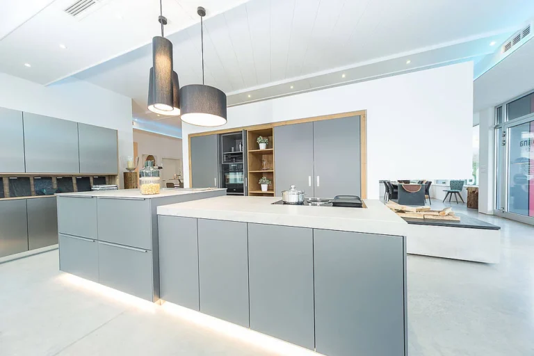 Küche in grau mit Arbeitsplatte in Betonoptik und Naturholzumrandung der Hochschränke