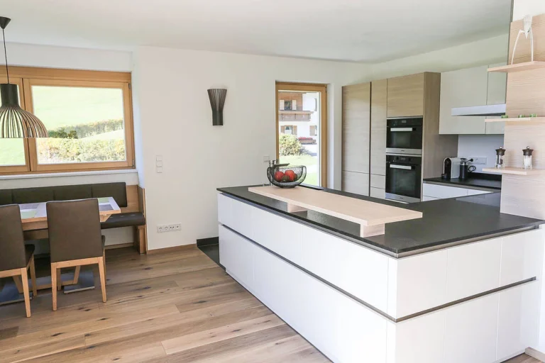 Moderne olina Küche - Hochschränke in Holz, Insel weiß mit Natursteinarbeitsplatte in schwarz